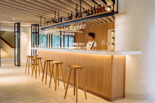 a woman standing behind a bar with stools at Inturotel Cala Esmeralda Beach Hotel & Spa - Adults Only in Cala d´Or