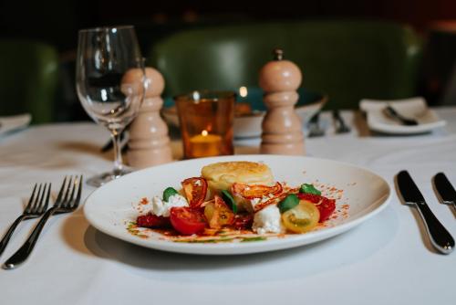 a plate of food on a table with a glass of wine at Spa Hotel at Ribby Hall Village in Wrea Green
