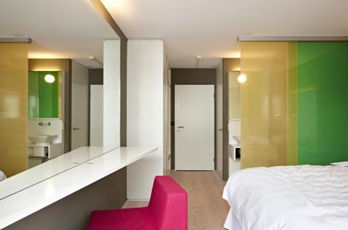 1 dormitorio con cama blanca y silla rosa en Hotel Restaurant Rössli en Bad Ragaz
