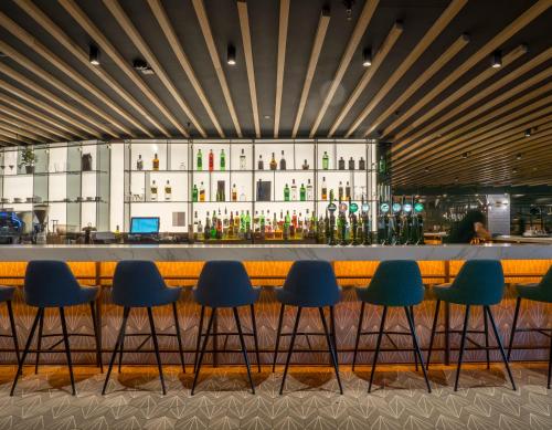 un bar dans un restaurant avec des chaises bleues dans l'établissement Pillo Hotel & Leisure Club, à Ashbourne