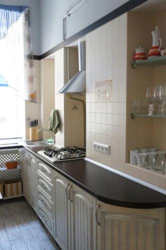 a kitchen with white cabinets and a black counter top at Apartment Glebova in Lviv