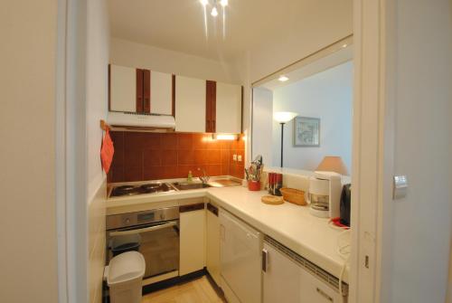 une petite cuisine avec des armoires blanches et un évier dans l'établissement Résidence Gray d'Albion Studio BRA507, à Cannes