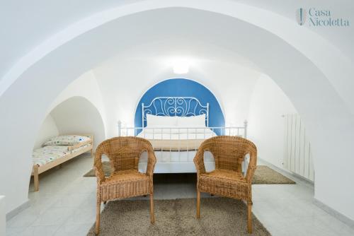ノーチにあるCasa Nicolettaのベッドルーム1室(ベッド1台、籐の椅子2脚付)