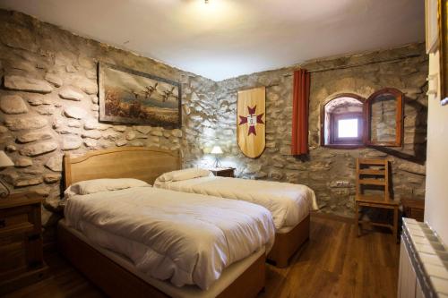 a bedroom with two beds and a stone wall at Castillo de Añón de Moncayo in Añón