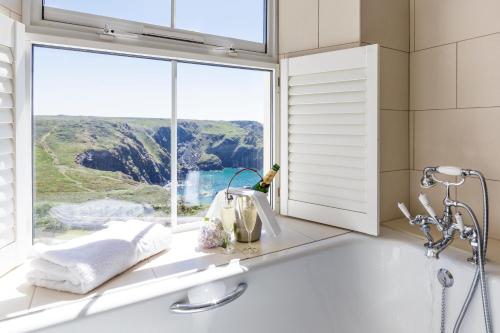 a bathroom with a bath tub and a window at Mullion Cove Hotel & Spa in Mullion