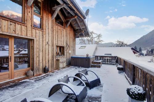 a snow covered patio with benches on a house at La Ferme du Lac Vert in Montriond