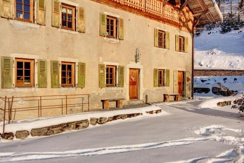 a building with green shuttered windows in the snow at La Ferme du Lac Vert in Montriond