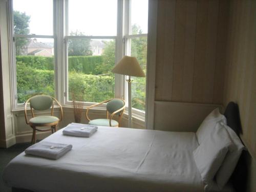 um quarto com uma cama, 2 cadeiras e uma janela em Murrayfield Park Guest House em Edinburgo