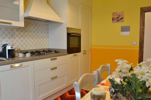 サン・カシャーノ・イン・ヴァル・ディ・ペーザにあるLa Casa di'Grilloのテーブル付きのキッチン、黄色い壁のキッチン
