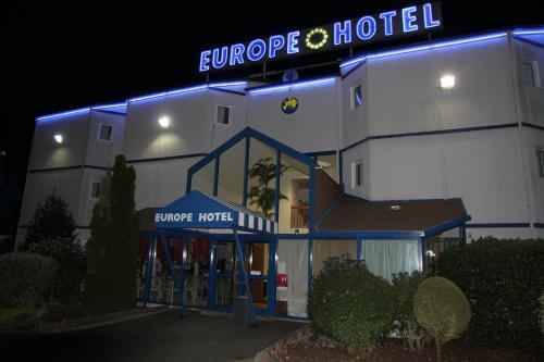 a hotel building with a blue lit sign on it at Europe Hôtel in Varennes Vauzelles