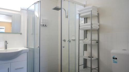 a bathroom with a glass shower and a sink at Highway Motor Inn Taree in Taree