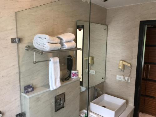 a bathroom with a mirror and a sink and towels at Hotel Ivory 32 in New Delhi