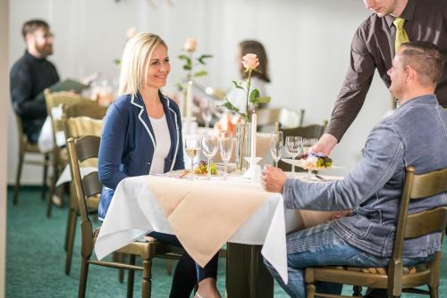 a man and woman sitting at a table in a restaurant at Das FRITZ Hotel Schwerin schöne Lage im Grünen mit regionaler Küche kostenfreien Parkplätzen und E Ladestation in Schwerin