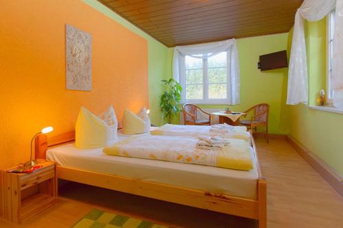 a bedroom with a bed with yellow walls and a window at Kräuterbaude in Saupsdorf