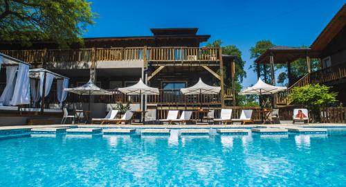 una gran piscina con sillas y sombrillas en BlackStone Apart Boutique Hotel en Villa General Belgrano