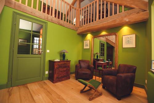 ein Wohnzimmer mit grünen Wänden und einer Treppe in der Unterkunft La petite Ferme in Chérence