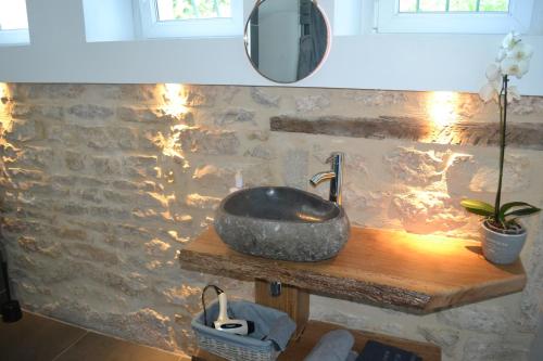 a bathroom with a stone sink on a wooden counter at Les Cottages de la Norge in Clénay