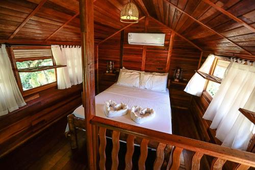 Habitación con cama en una cabaña de madera en Pousada Recanto das Aves, en Iguape