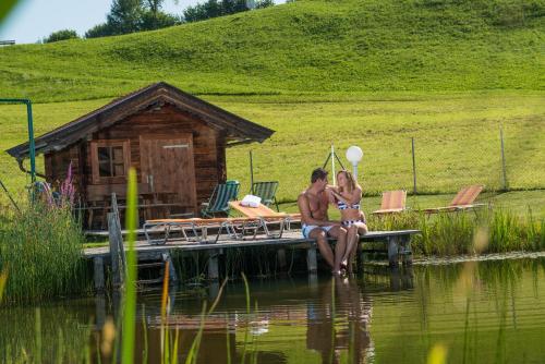 a man and a woman sitting on a dock on the water at Der Schwendterwirt in Schwendt