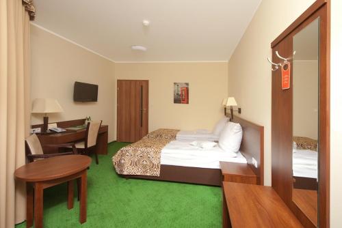 a hotel room with a bed and a table and a desk at Hotel Zielony in Poznań