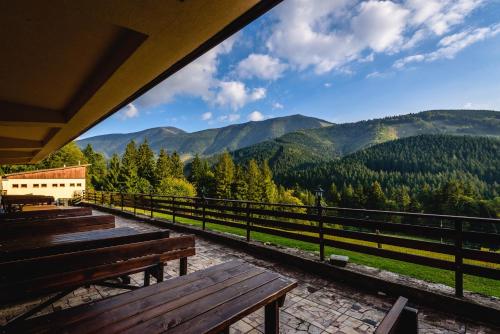 a wooden bench in front of a mountain range at Hotel Boboty in Terchová