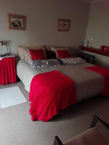 two beds in a hotel room with red sheets at The Olde House in Port Elizabeth