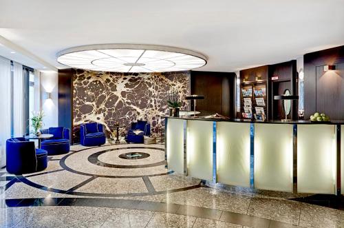 a lobby with blue chairs and a reception desk at Seaside Park Hotel Leipzig in Leipzig