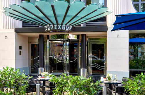 a restaurant with tables and chairs in front of a building at Seaside Park Hotel Leipzig in Leipzig
