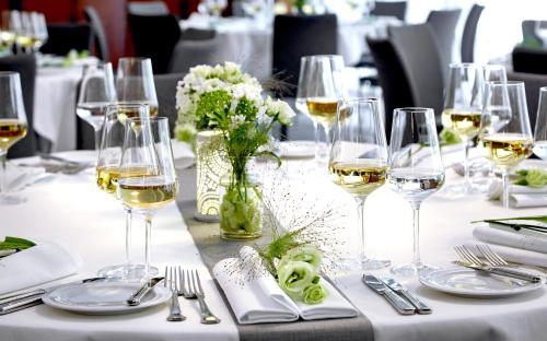 a table with glasses of wine and flowers on it at Seaside Park Hotel Leipzig in Leipzig