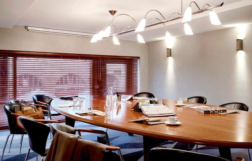 a conference room with a large wooden table and chairs at Seaside Park Hotel Leipzig in Leipzig