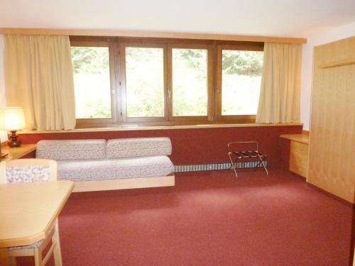 a living room with a couch and some windows at Ambiez Residencehotel in Madonna di Campiglio