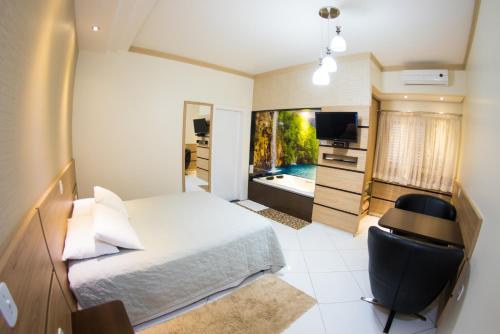 sypialnia z łóżkiem, biurkiem i telewizorem w obiekcie Hotel Tito's w mieście Capanema