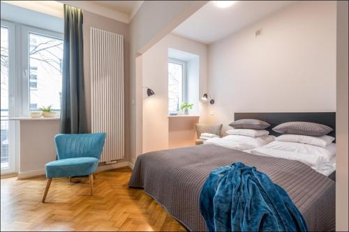 a bedroom with a large bed and a blue chair at P&O Apartments Poznańska in Warsaw