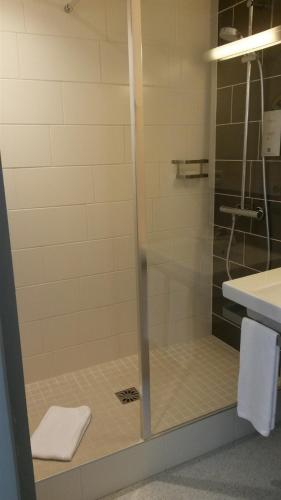 a shower with a glass door in a bathroom at Hôtel de La Cloche in Dole