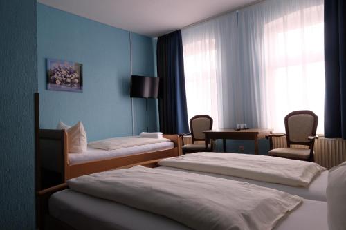 a hotel room with two beds and a table and chairs at Hotel Grüner Kranz in Rendsburg