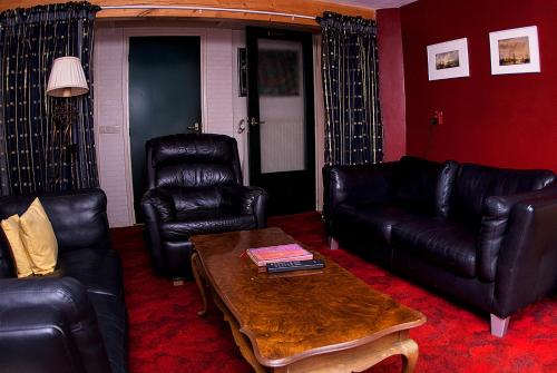 a living room with black leather furniture and a coffee table at B&B De Oude Molensteen in Eelde-Paterswolde
