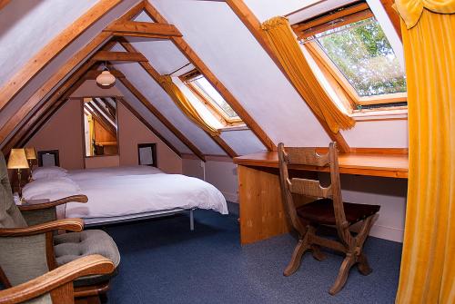 een slaapkamer met een bed, een bureau en ramen bij B&B De Oude Molensteen in Eelde-Paterswolde