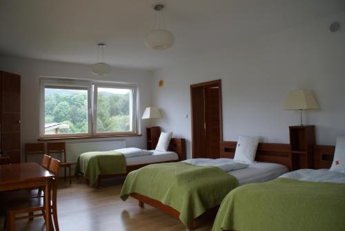 a hotel room with three beds and a window at Willa Moja Gawra in Lądek-Zdrój