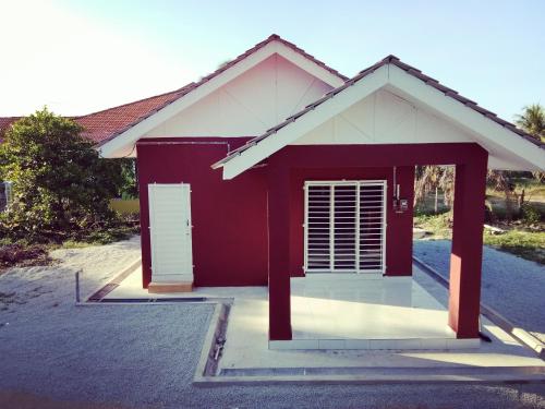 una casa roja y blanca con garaje en Homestay AZMI ZITA, en Kuala Terengganu