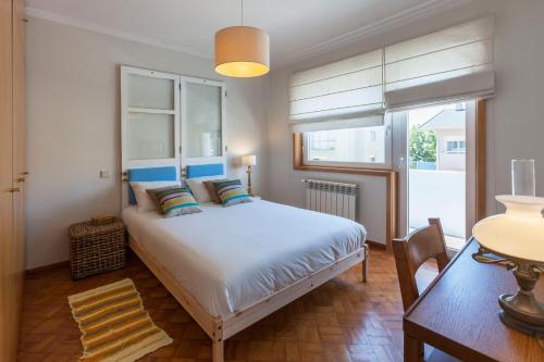 Schlafzimmer mit einem Bett, einem Tisch und einem Fenster in der Unterkunft Family House in Vila Nova de Gaia
