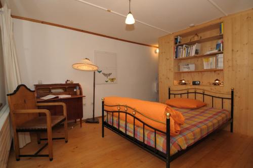 a bedroom with a bed and a desk and a chair at BnB Hasatrog Jenaz in Jenaz