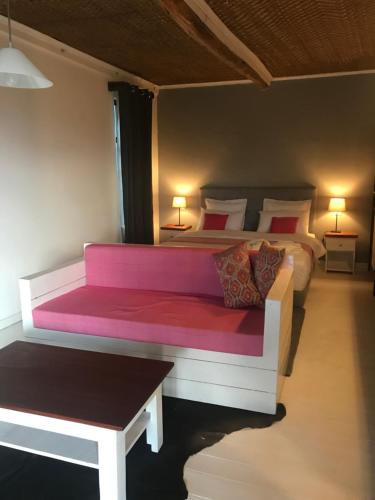a bedroom with two beds and a pink bench at Pili Pili Boutique Hotel in Kigali