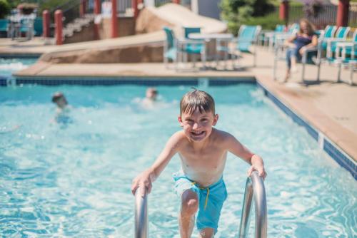 a young boy is going down the stairs in a swimming pool at Atlantis Family Waterpark Hotel, an Ascend Collection Hotel in Wisconsin Dells