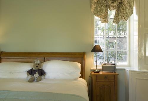 a teddy bear sitting on a bed next to a window at Trigony Hotel and Garden Spa in Closeburn