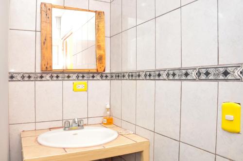 a bathroom with a sink and a mirror at La Hacienda Rooms & Food in Jacó
