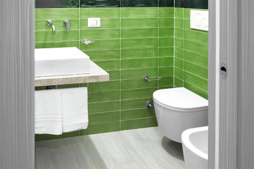 a green tiled bathroom with a toilet and a sink at B&B JONIO Roma in Rome