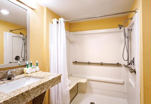 uma casa de banho com um lavatório e um chuveiro em Holiday Inn Express & Suites Oceanfront Daytona Beach Shores, an IHG Hotel em Daytona Beach