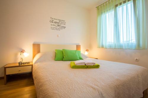 a bedroom with a bed with green pillows and a window at Apartman Irena in Pula