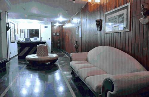 a living room with a couch and a chair at Hotel Plaza Inn Flat Residence in Alfenas