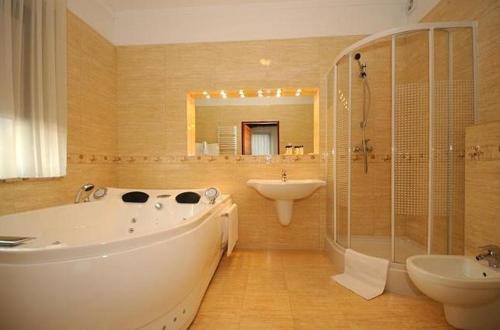 y baño con bañera, lavamanos y ducha. en Hotel Salamandra en Hoczew